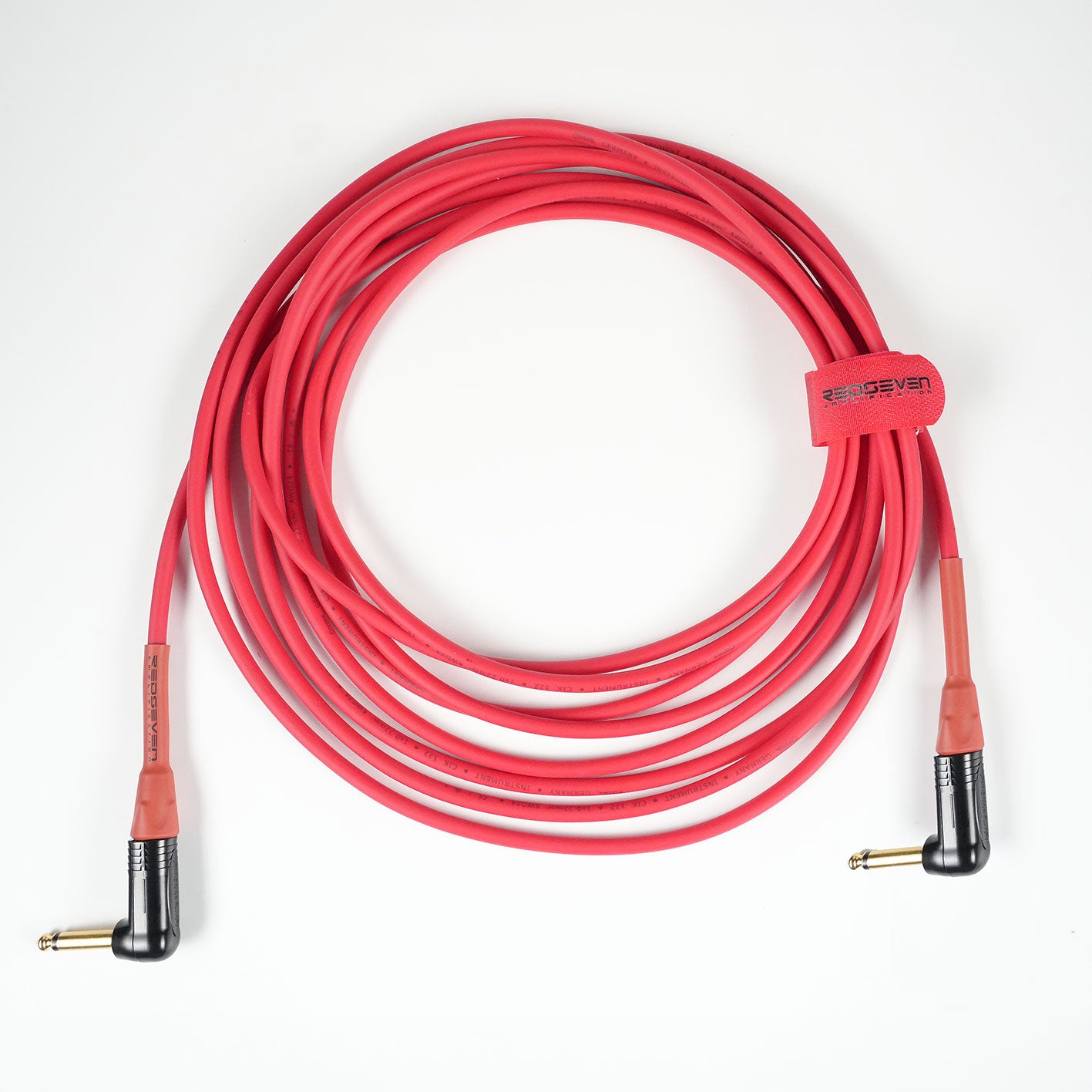 Master Signature instrument cable, RedSeven x Cordial, right angle 1,4 inch jacks, coiled cable on white background