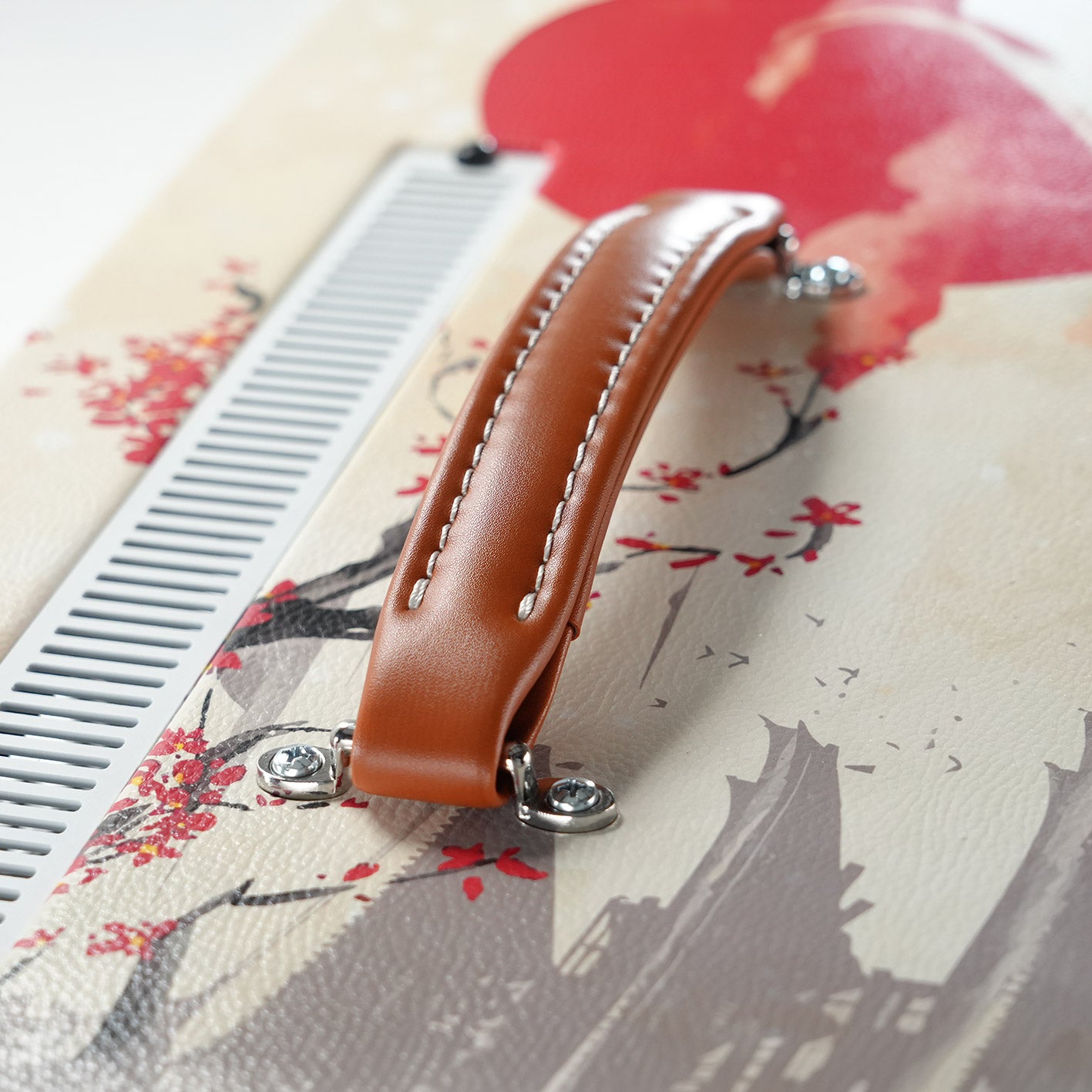 Leviathan Japan Serie Koi — tan leather handle close-up with sakura and red sun background